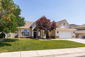 View of front facade featuring brick siding, driveway, a gate, stucco siding, and a garage