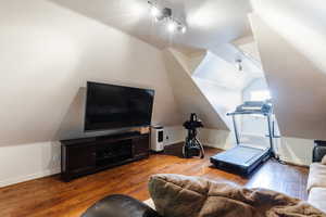 Living area with hardwood / wood-style floors and vaulted ceiling