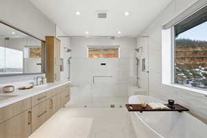 Full bath with double vanity, plenty of natural light, a soaking tub, and a stall shower