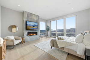 Bedroom with wood-type flooring, a tile fireplace, and recessed lighting