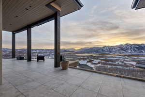 Snow covered patio with a mountain view and a patio area