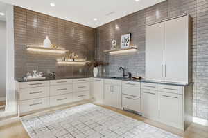 Kitchen with open shelves, dark countertops, light wood-style floors, and modern cabinets