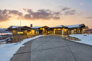 View of front of home with stone siding, an attached garage, a chimney, and concrete driveway