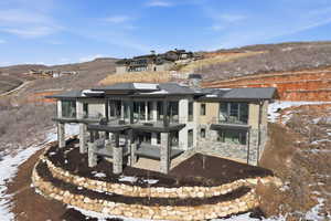Snow covered house featuring a chimney, stone siding, and a patio area