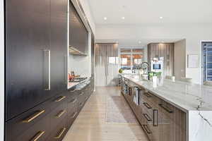 Kitchen featuring modern cabinets, light stone counters, light wood finished floors, tasteful backsplash, and stainless steel gas stovetop