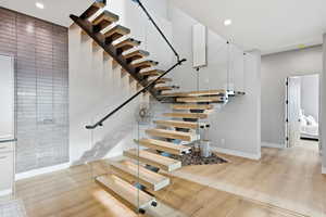 Stairs with wood finished floors and recessed lighting