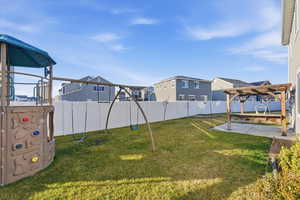 Fenced backyard with a playground, a pergola, a residential view, and a patio area