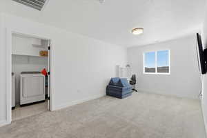 Unfurnished room featuring light colored carpet, a textured ceiling, an office area, and washer and dryer
