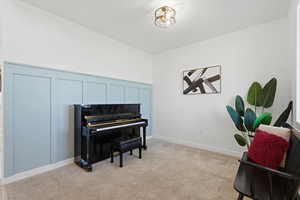 Living area with light colored carpet and a decorative wall