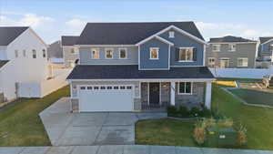 View of front of home with covered porch, a residential view, driveway, and stone siding
