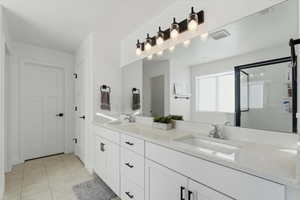 Bathroom with double vanity, a shower stall, and light tile patterned floors