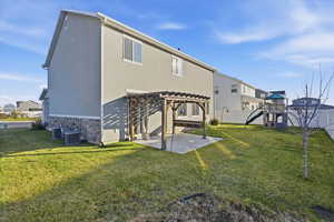 Rear view of property featuring a pergola, a patio, stone siding, and stucco siding