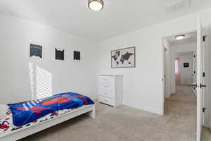 Bedroom featuring light carpet and attic access