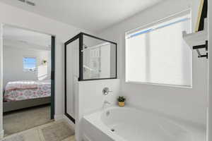 Ensuite bathroom featuring a bath, a shower stall, light tile patterned floors, and light colored carpet