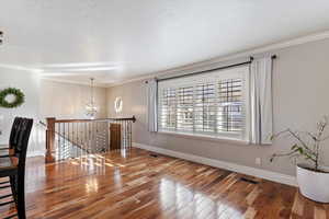 Spare room featuring hardwood / wood-style floors, a chandelier, and ornamental molding