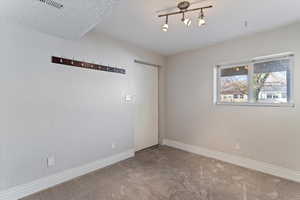 Empty room with light colored carpet and a textured wall