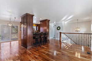 Bar area featuring a chandelier, hanging light fixtures, plenty of natural light, and ornamental molding