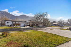 View of front of home with a residential view, a mountain view, driveway, a front yard, and a garage