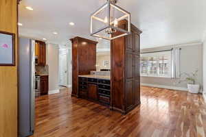 Kitchen with appliances with stainless steel finishes, light stone counters, backsplash, crown molding, and dark wood-type flooring