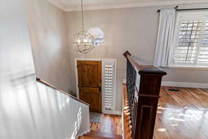 Foyer with hardwood / wood-style floors, a chandelier, crown molding, and stairs