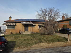 Single story home with a front lawn, brick siding, and a chimney