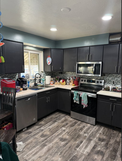 Kitchen featuring appliances with stainless steel finishes, light countertops, dark cabinetry, new Lifeproof flooring, and a textured ceiling