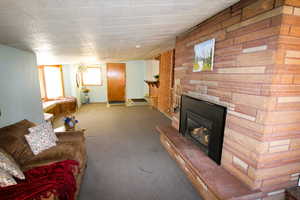 Carpeted family room with a large fireplace and a brick wall, a fireplace and window seat