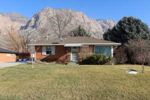 Single story home with a front lawn, brick siding, and a mountain view