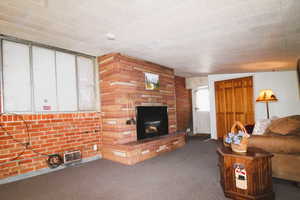 Carpeted family room with a large fireplace and a brick wall, fireplace and window seat