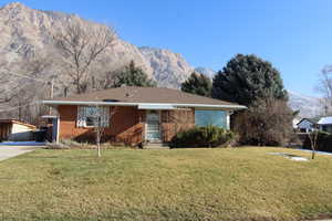 Ranch-style home with a mountain view, a front yard, and brick siding
