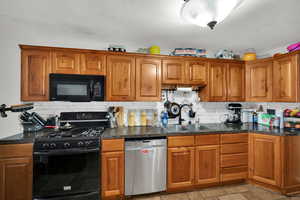 Kitchen featuring black appliances, brown cabinetry, backsplash, and stone tile floors