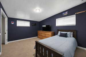 Bedroom with vaulted ceiling and light carpet