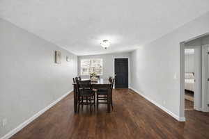 Dining space with dark wood-style flooring and a textured ceiling