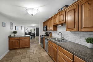 Kitchen featuring wood finish cabinets, stainless steel appliances, stone tile flooring, and decorative backsplash