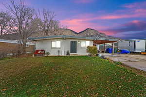 View of front facade featuring an attached carport, a patio, a yard, driveway, and brick siding
