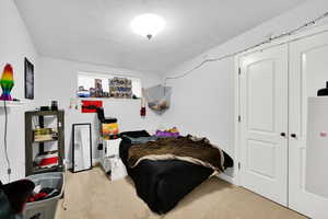 Bedroom with a textured ceiling, a closet, and light carpet