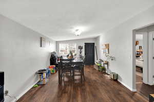 Dining area with dark wood-style floors and a textured ceiling