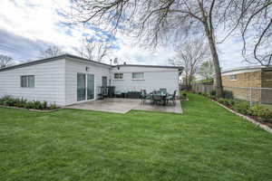 Rear view of property with a fenced backyard, a patio area, brick siding, and outdoor dining space