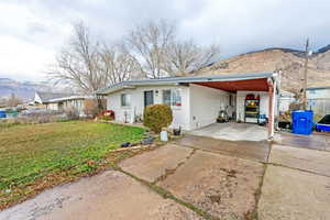 View of front facade with a mountain view, concrete driveway, a carport, brick siding, and a patio area