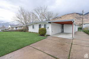View of front facade featuring a mountain view, brick siding, an attached carport, and driveway
