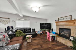 Living area featuring a tile fireplace, dark wood finished floors, and beamed ceiling