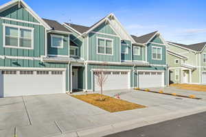 Craftsman-style home featuring board and batten siding, a standing seam roof, driveway, a metal roof, and an attached garage