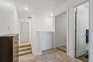 Hall featuring an upstairs landing, light colored carpet, stairway, and recessed lighting