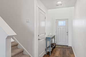Entrance foyer with dark wood-style floors and stairs