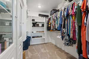 Walk in closet with light colored carpet