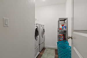 Laundry room with washing machine and dryer and dark wood-type flooring