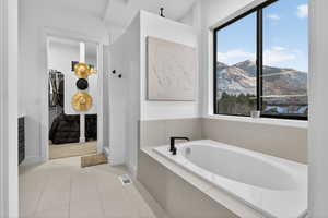 Full bathroom featuring a bath, a mountain view, light tile patterned floors, walk in shower, and a walk in closet
