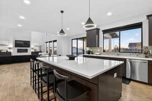 Kitchen featuring a kitchen bar, stainless steel dishwasher, open floor plan, pendant lighting, and a center island