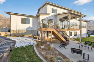 Back of property featuring a mountain view, a patio area, stairway, stucco siding, and a yard