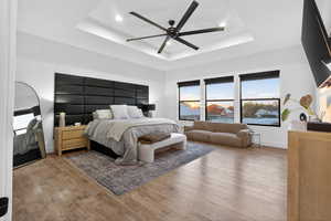 Bedroom featuring hardwood / wood-style flooring, ceiling fan, a tray ceiling, and recessed lighting